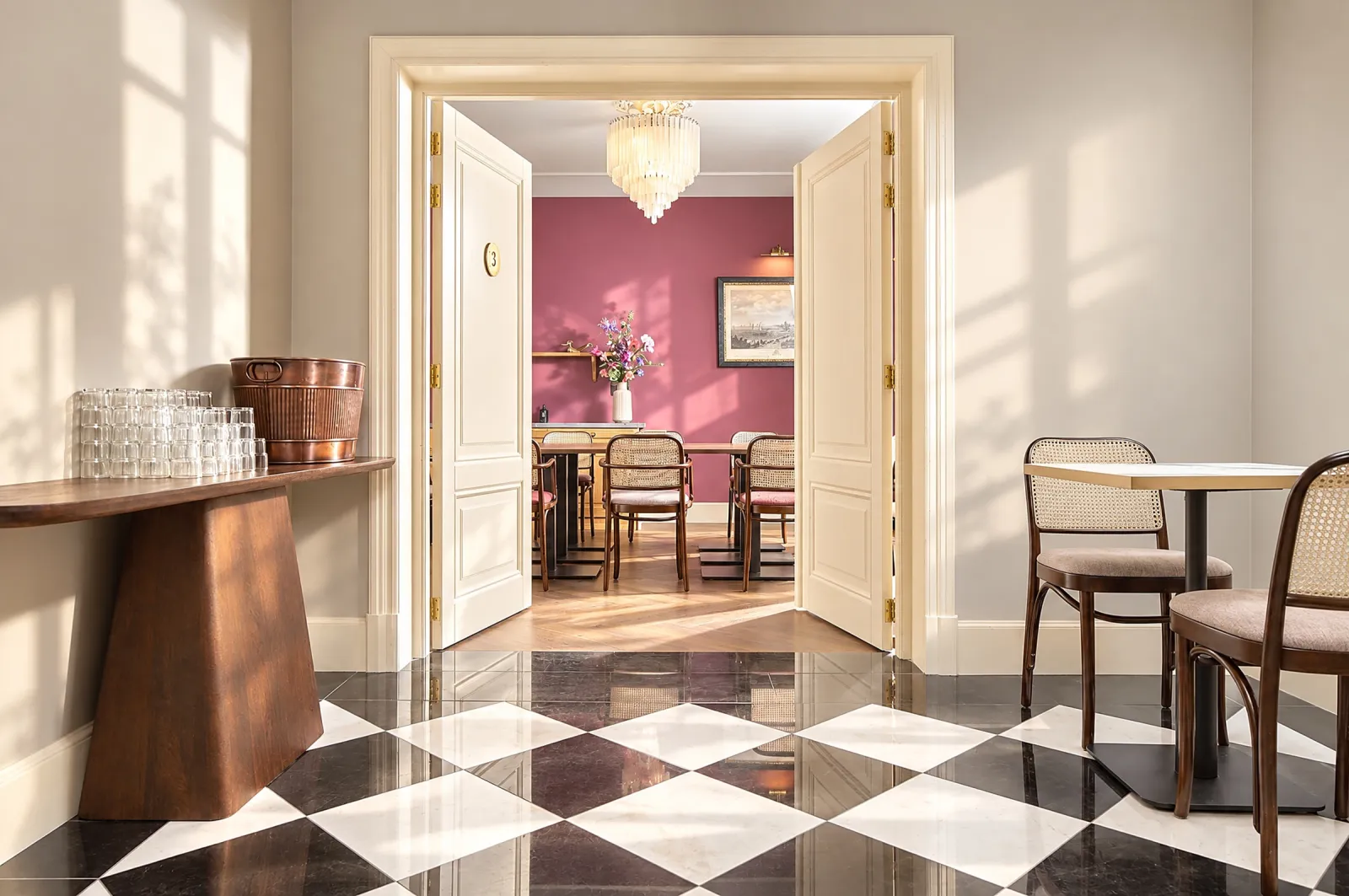 View from the chequered hallway through double doors into a pink dining room
