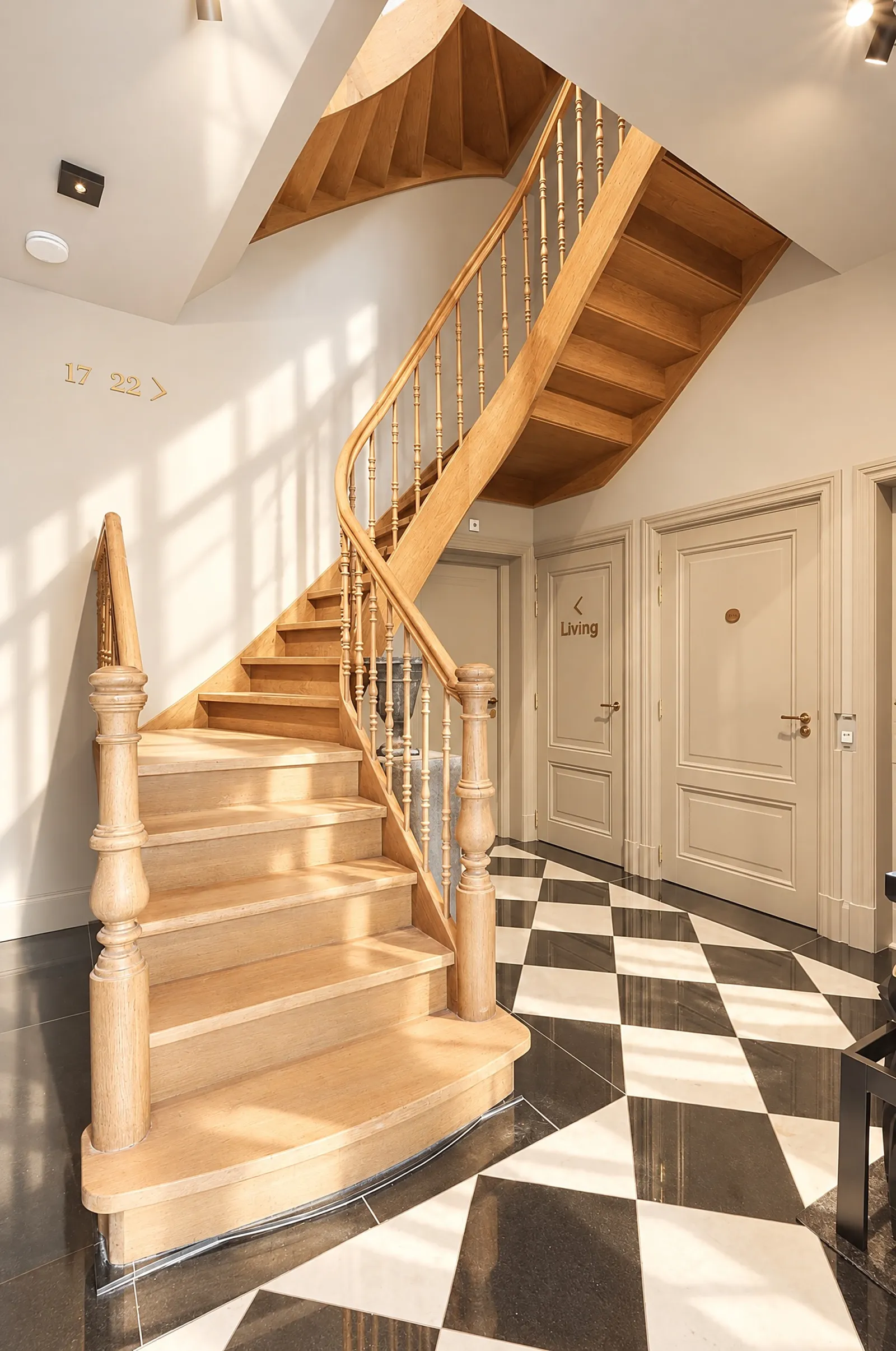 Hallway with a curving oak staircase and black-and-white marble floor
