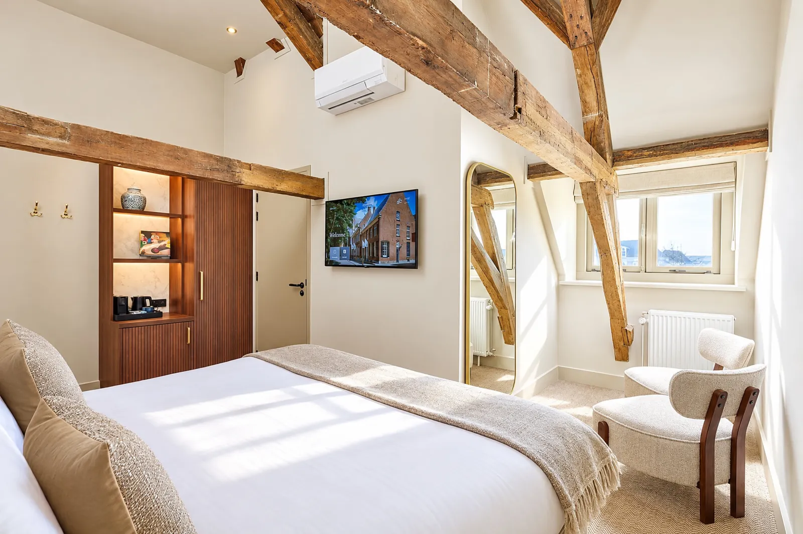 Comfort-kamer onder het dak met eikenhouten balken, tweepersoonsbed en bouclé stoel
